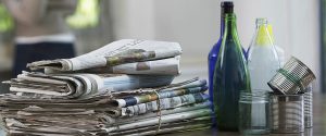 newspapers, glass bottles, and aluminum can sitting on table